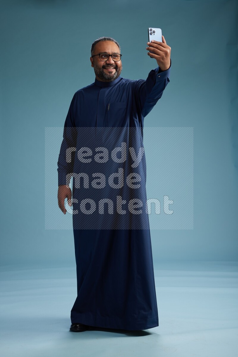 Saudi Man without shimag Standing taking selfie on blue background