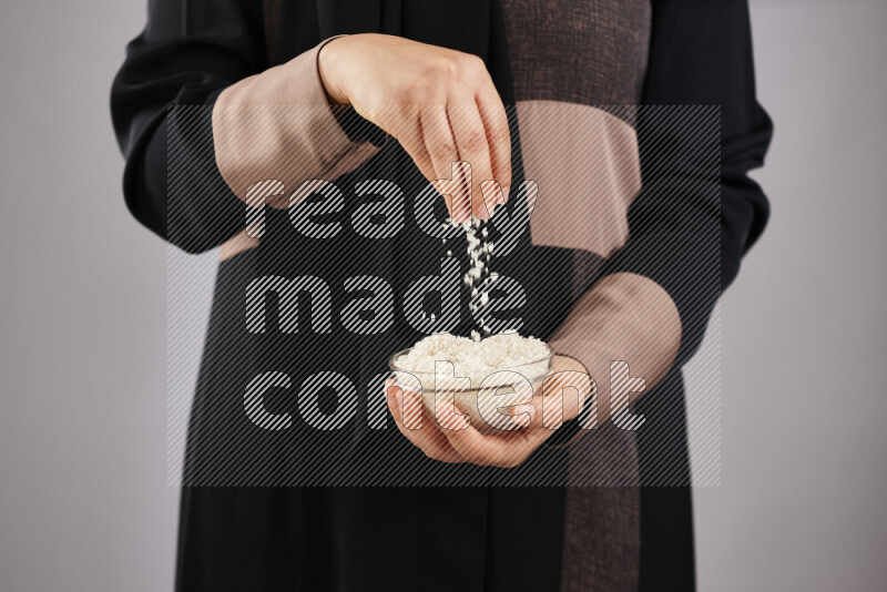 Woman in abaya holding different kinds of legumes in different positions