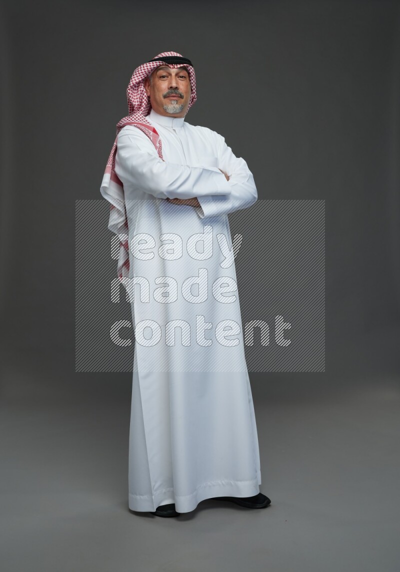 Saudi man with shomag Standing Interacting with the camera on gray background
