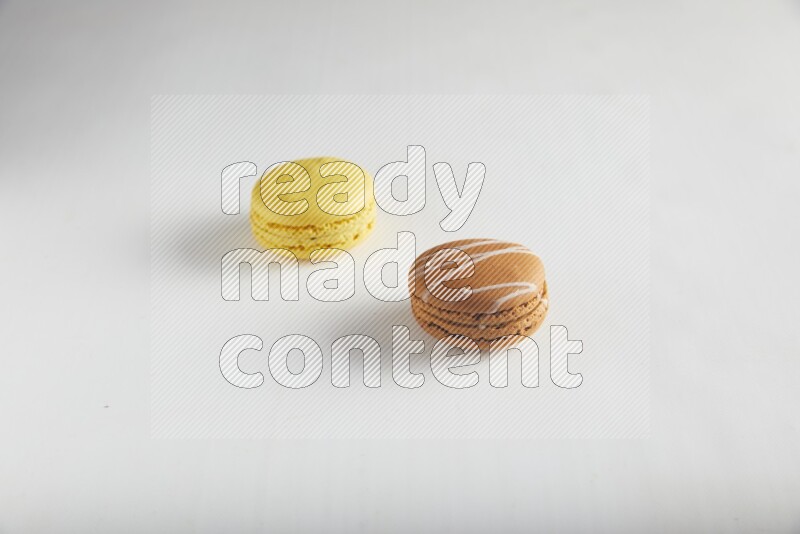 45º Shot of of two assorted Brown Irish Cream, and Yellow Lemon macarons on white background