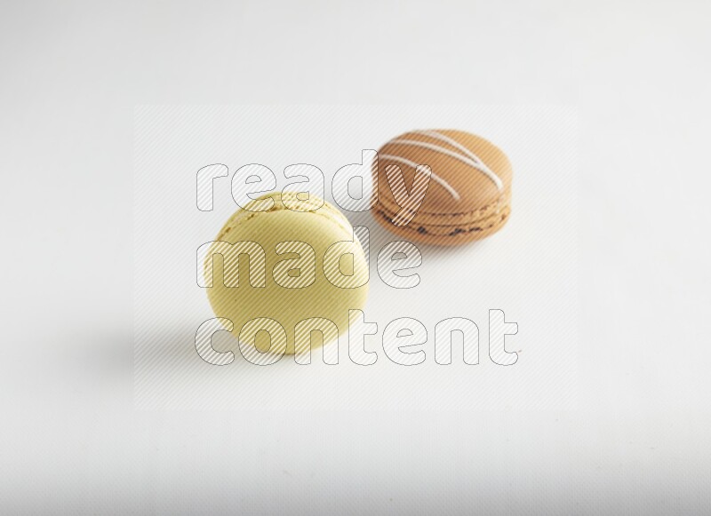 45º Shot of of two assorted Brown Irish Cream, and Yellow Lime macarons on white background