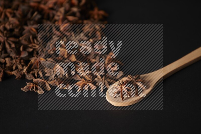 اليانسون النجمي في ملعقة خشبية ومتناثر على أرضية سوداء