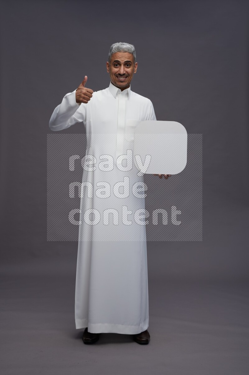 Saudi man wearing thob standing holding social media sign on gray background