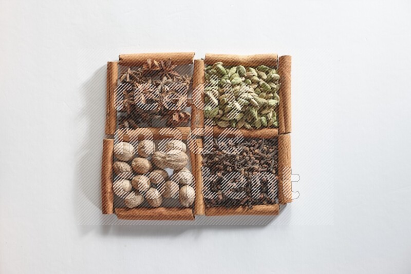 4 squares of cinnamon sticks full of cardamom, star anise, cloves and nutmeg on white flooring
