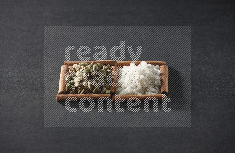 2 squares of cinnamon sticks full of white salt and cardamom on black flooring