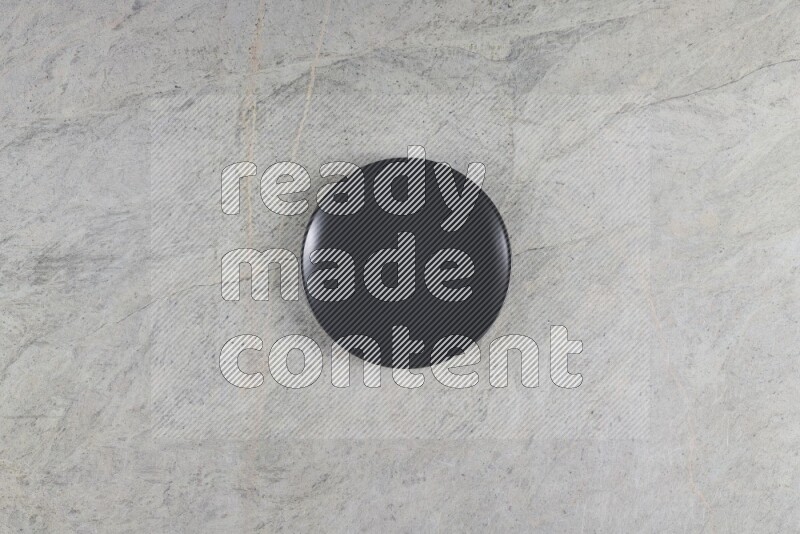 A black ceramic circular plate on grey marble background