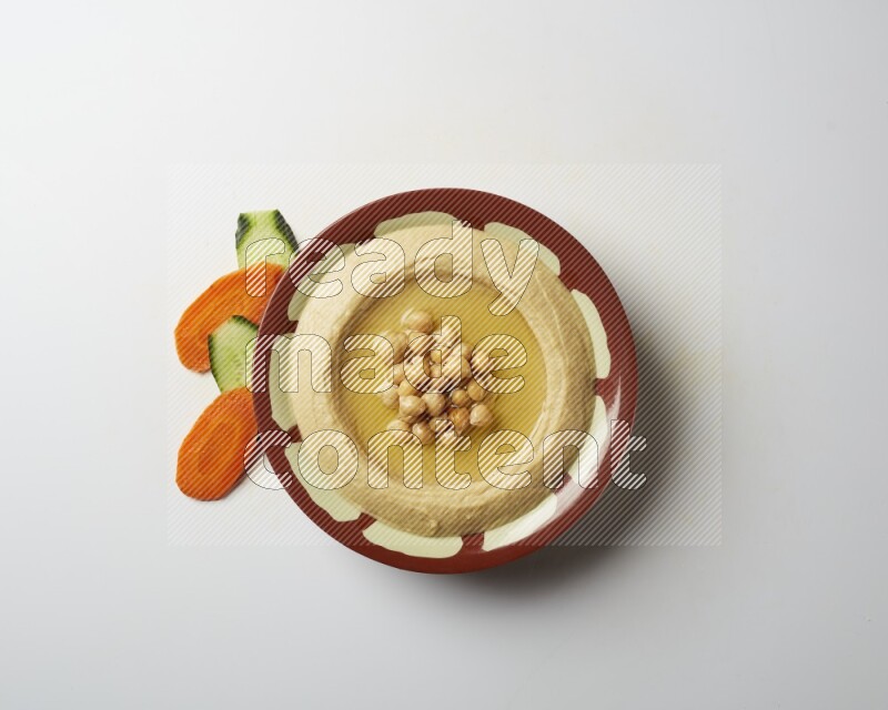 Hummus in a traditional plate garnished with roasted chickpeas  on a white background