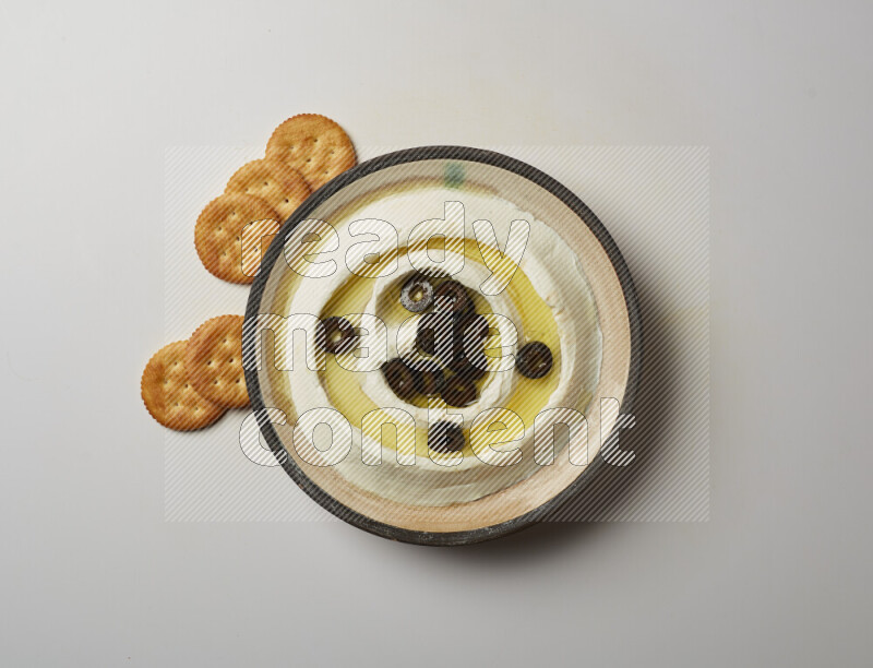 Lebnah garnished with sliced olives in a pottery plate on a white background
