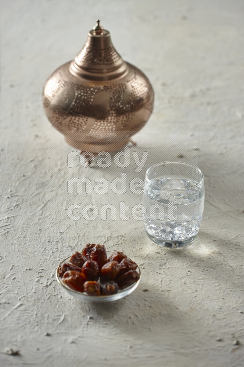 A golden lantern with different drinks, dates, nuts, prayer beads and quran on textured white background