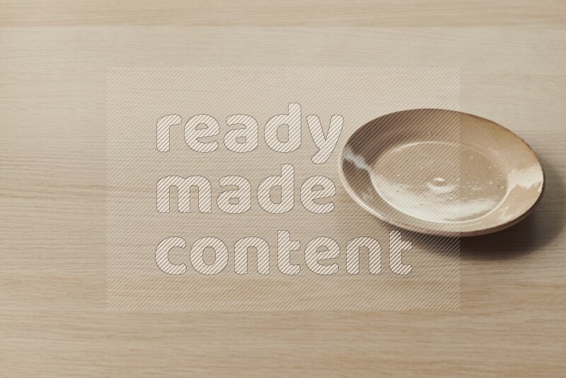 A beige pottery plate on light wooden background