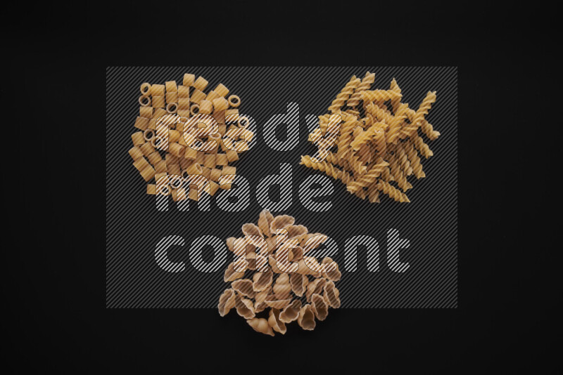Different pasta types in bunches on black background