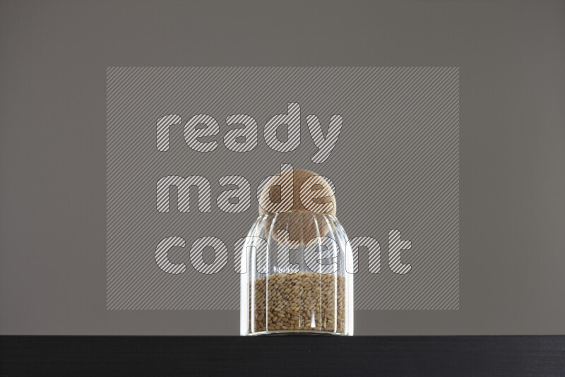 Hulled wheat in a glass jar on black background