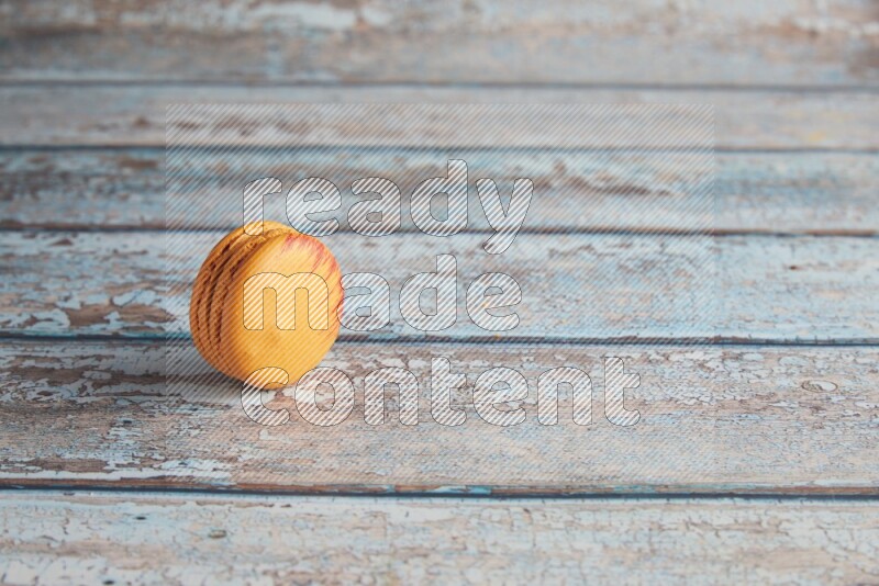 45º Shot of Orange Exotic macaron on light blue wooden background
