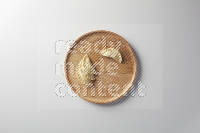Four Sambosas on a wooden round plate on a white background
