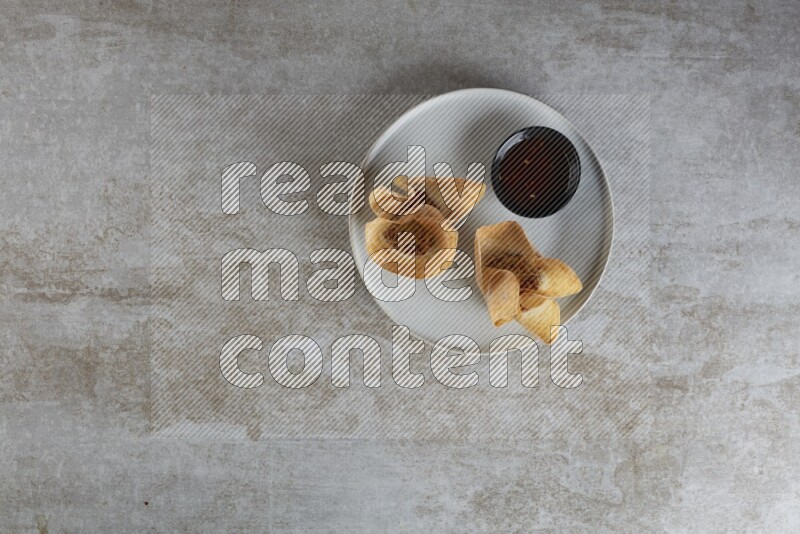 wonton cups with soy sauce ramkin on grey ceramic plate on grey textured counter top