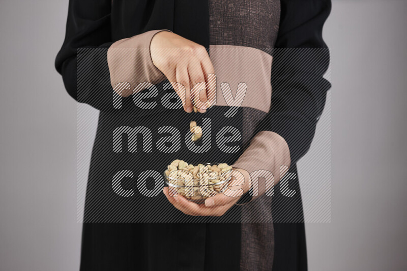 Woman in abaya holding different kinds of legumes in different positions