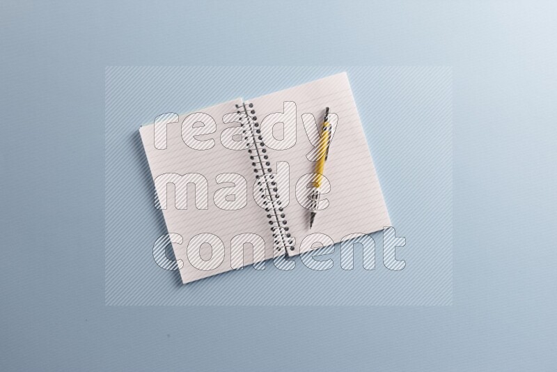 A blank open notebook with different school supplies on blue background