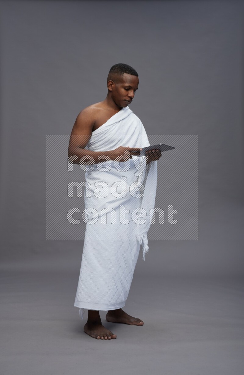 A man wearing Ehram Standing working on tablet on gray background