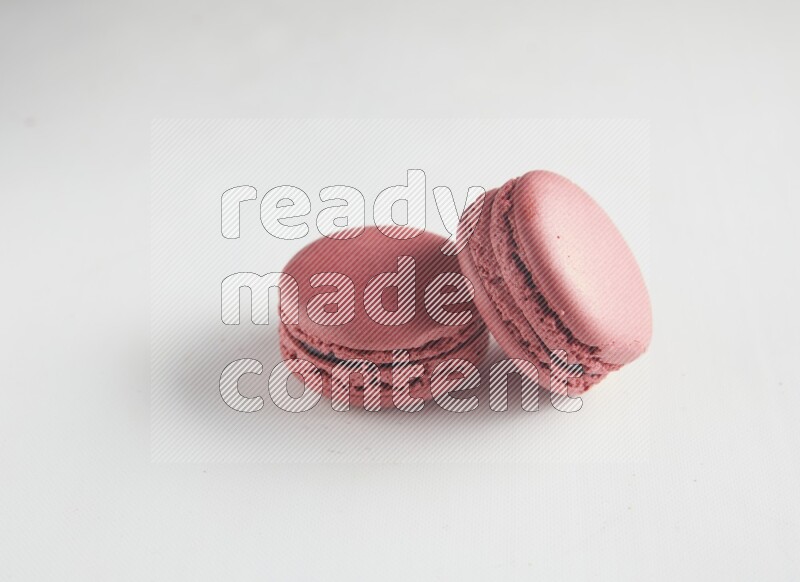 45º Shot of two Pink Raspberry macarons on white background