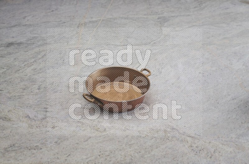 A small copper pan on grey marble background