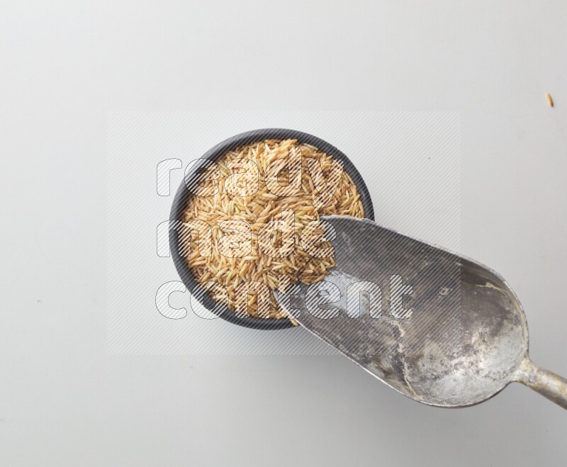 Top-view shot of long grain brown rice in a container on white background