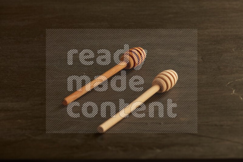 Wooden honey dipper on black slate background