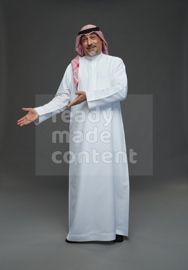 Saudi man with shomag Standing Interacting with the camera on gray background
