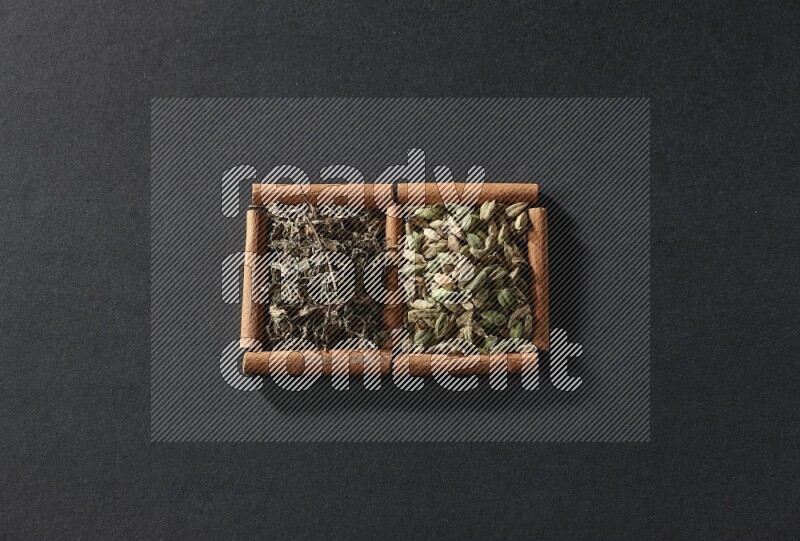 2 squares of cinnamon sticks full of cardamom and dried basil on black flooring