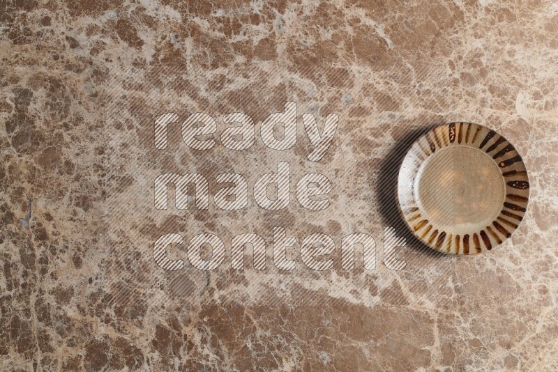 A multicolored pottery plate on beige marble background