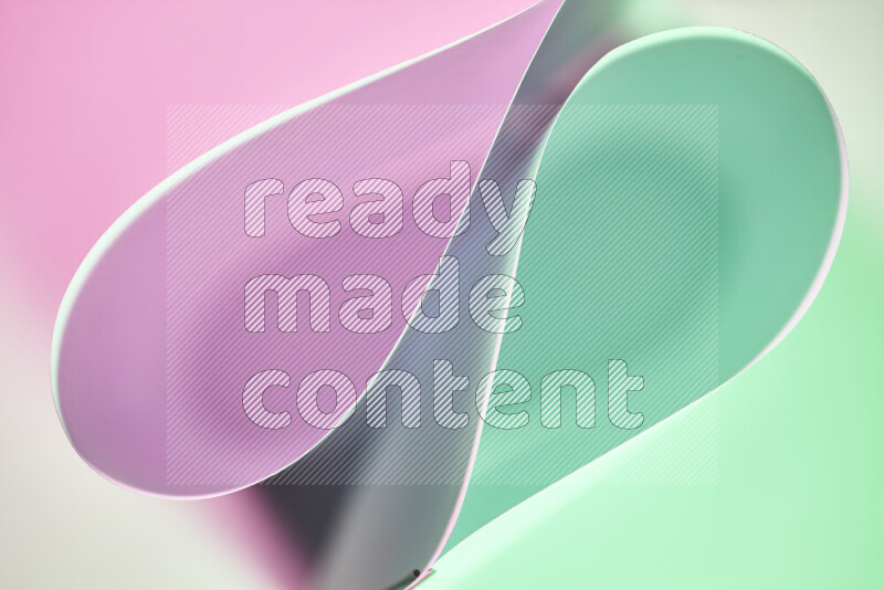 An abstract art of paper folded into smooth curves in green and pink gradients