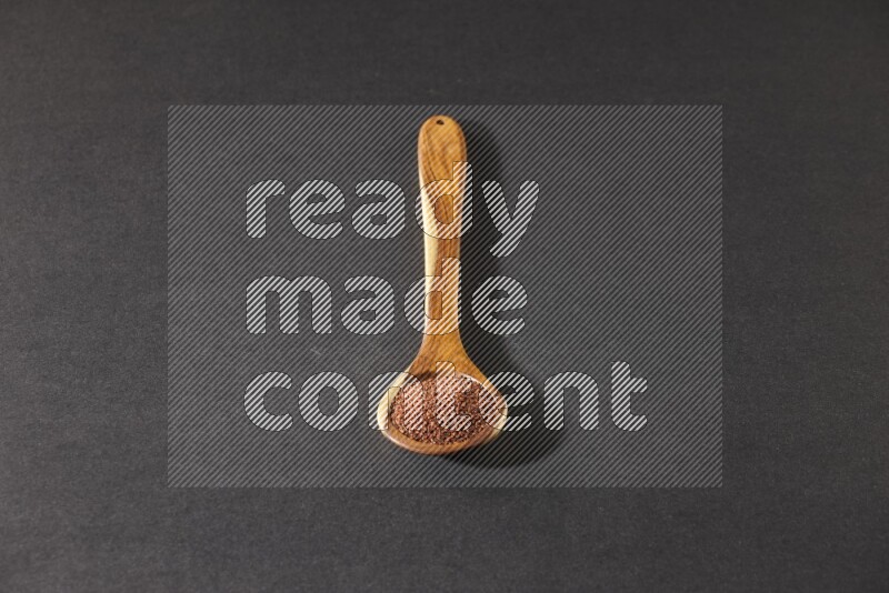 ملعقة خشبية كبيرة ممتلئة ببذور حب الرشاد علي خلفية سوداء