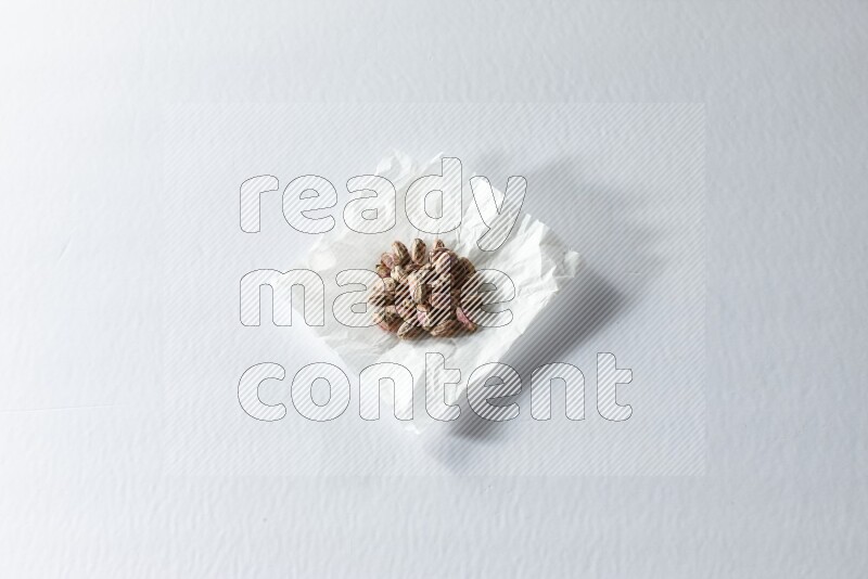 Peeled pistachios on a crumpled piece of paper on a white background in different angles