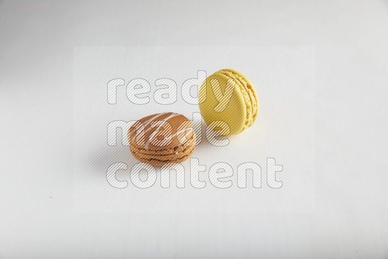 45º Shot of of two assorted Brown Irish Cream, and Yellow Lemon macarons on white background
