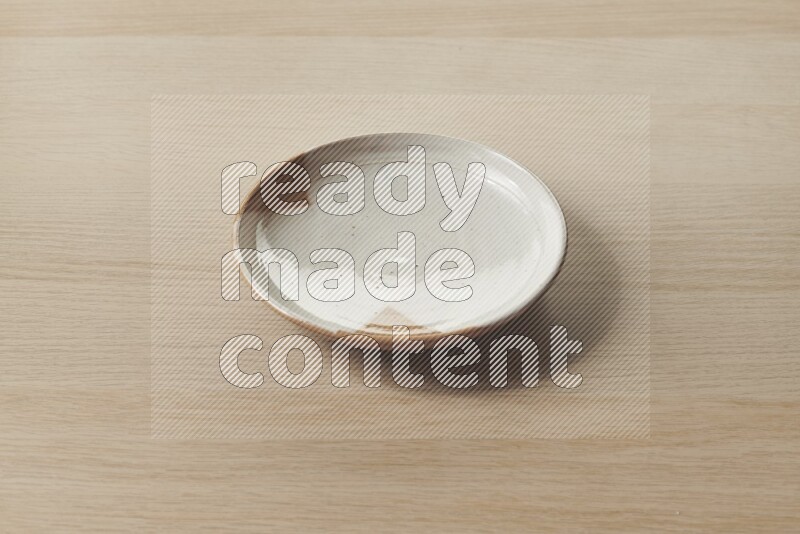 A multicolored pottery plate on light wooden background