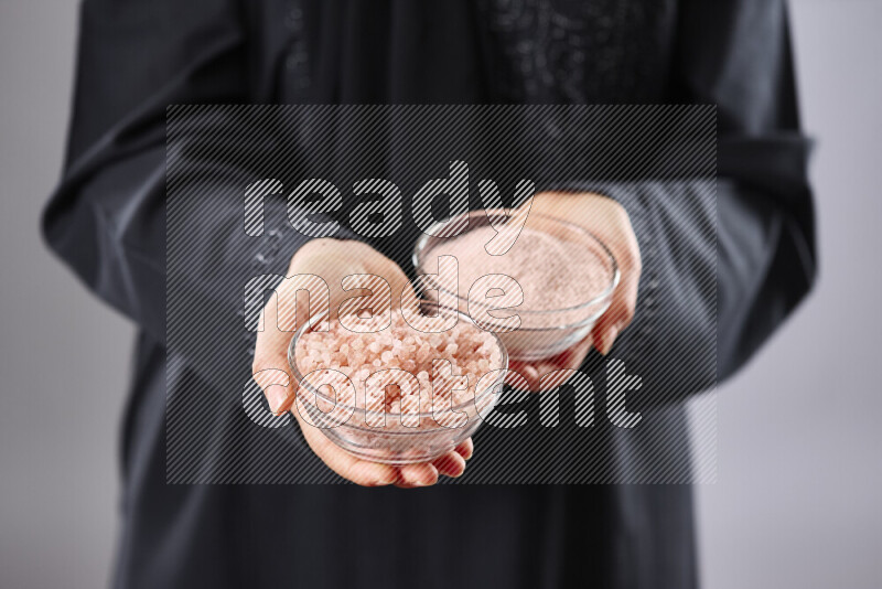 Woman in abaya holding different kinds of spices in different positions
