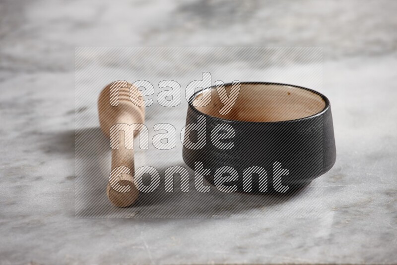 Multicolored pottery bowl with wooden honey dipper on the side on grey marble background
