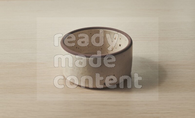 A beige pottery oven bowl on light wooden background