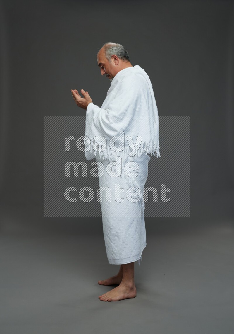 A man wearing Ehram Standing dua'a on gray background