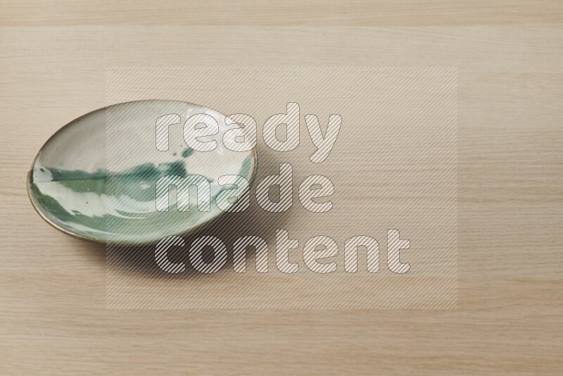 A multicolored pottery plate on light wooden background