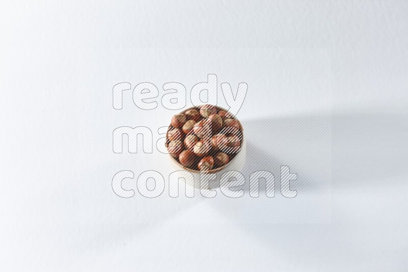 A beige ceramic bowl full of hazelnuts on a white background in different angles
