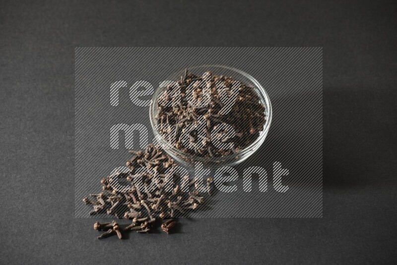 A glass bowl full of cloves on a black flooring
