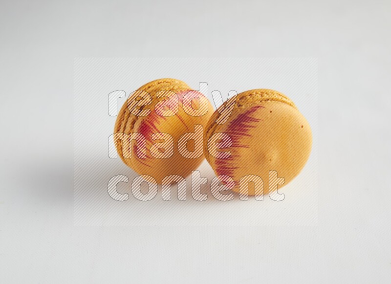 45º Shot of two orange Exotic macarons on white background