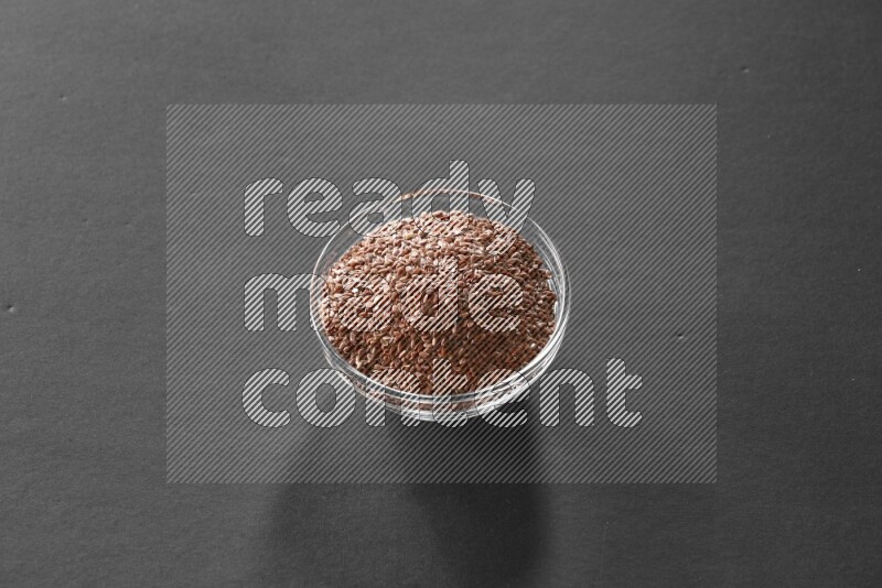 A glass bowl full of flax on black flooring