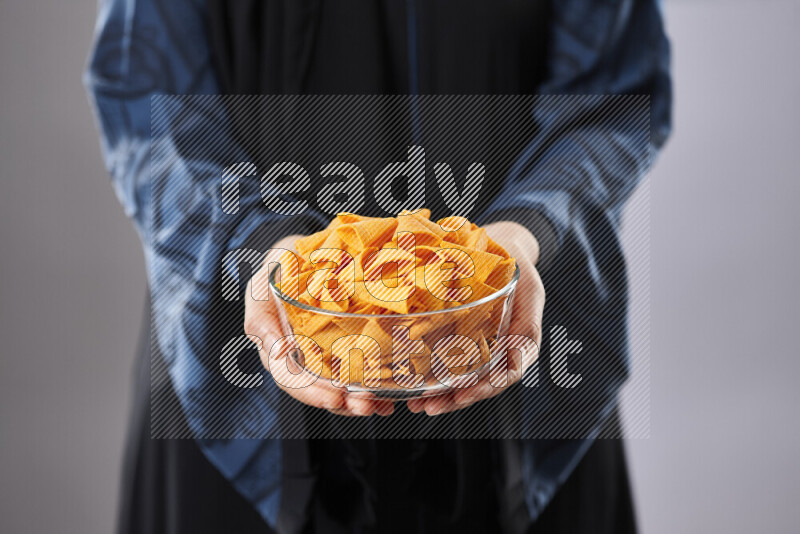 Woman in abaya holding different kinds of snacks in different positions