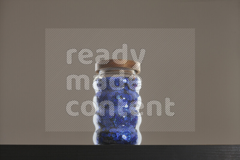 Sequins in a glass jar on black background