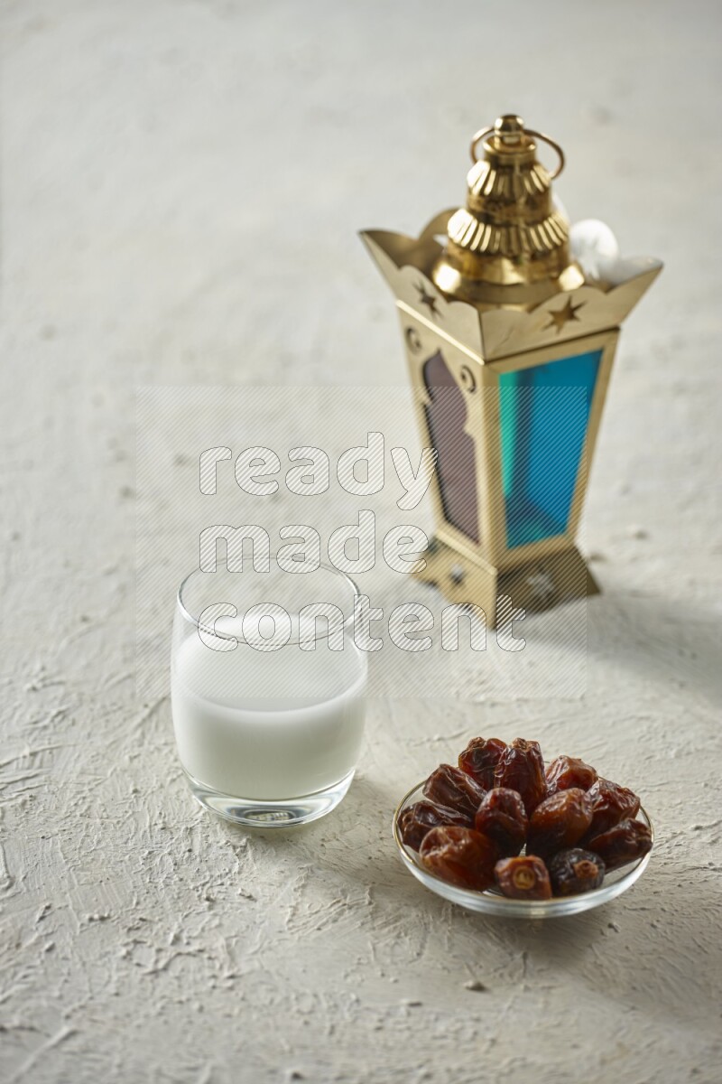A golden lantern with different drinks, dates, nuts, prayer beads and quran on textured white background