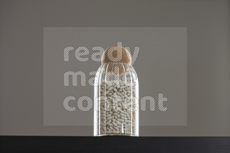 White beans in a glass jar on black background