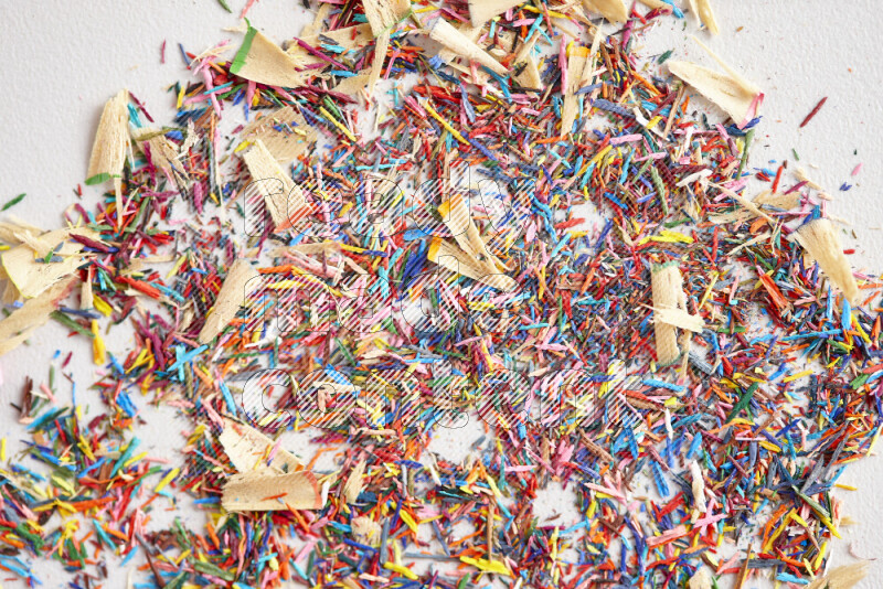 This image showcases a vibrant multicolored pencil shavings scattered on grey background