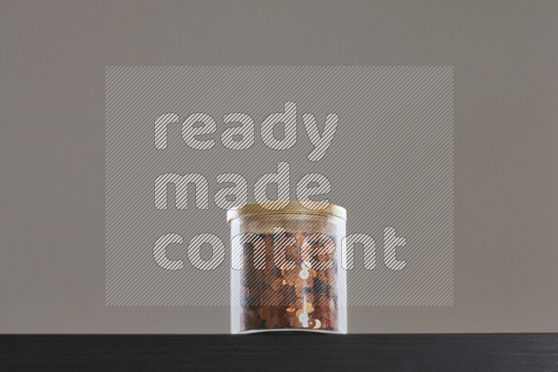 Sequins in a glass jar on black background