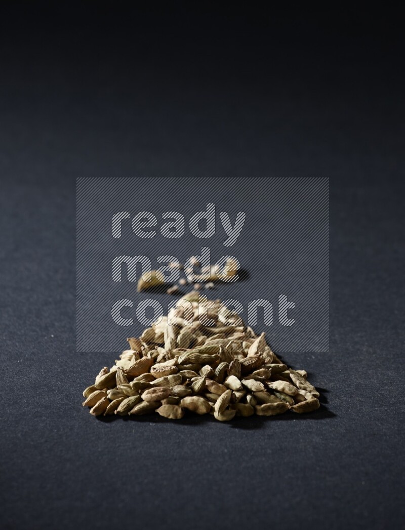 Cardamom in a triangle shape on black flooring
